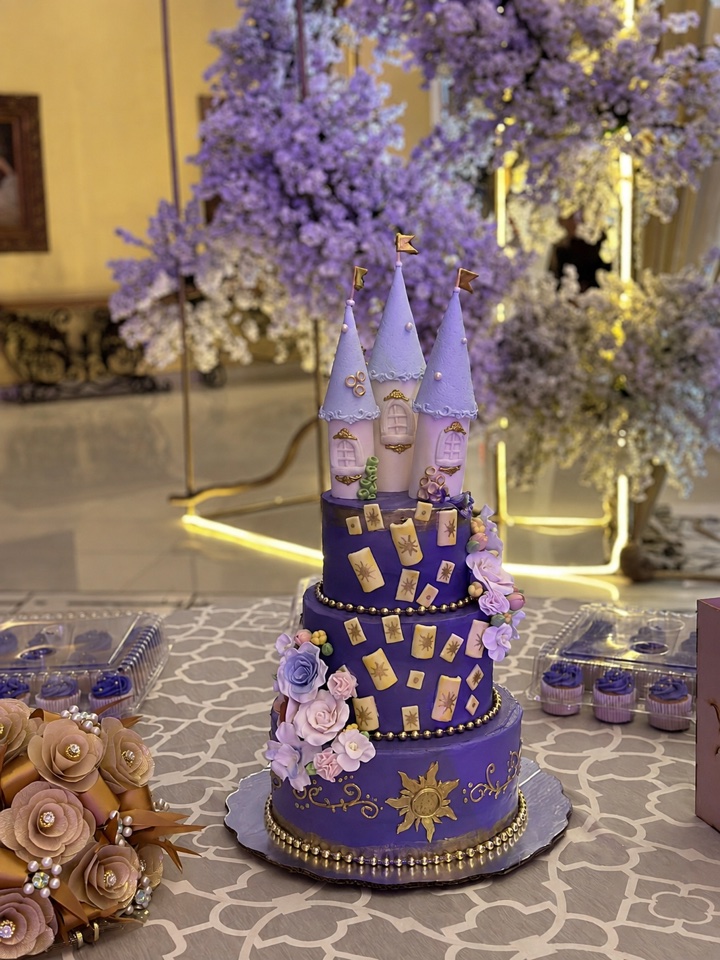 Pastel de XV años de tres pisos en morado con castillo y detalles dorados