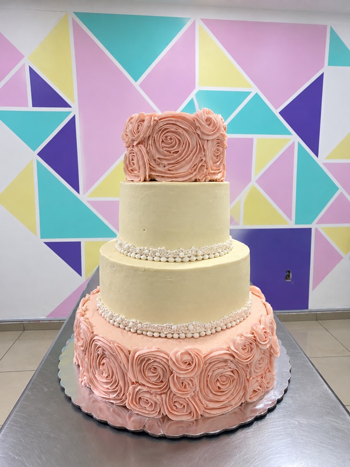 Pastel de XV años de tres pisos con rosetones color durazno y perlas de azúcar